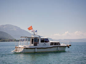 A picturesque view of a yacht cruising on tranquil waters, showcasing its elegant design against a backdrop of mountains — perfect for scenic boat tours.