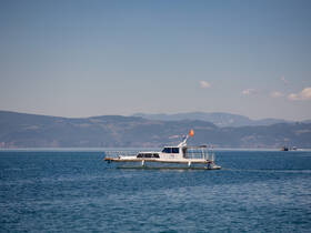A sleek speedboat navigates the tranquil waters, surrounded by picturesque mountains — ideal for scenic tours or leisurely outings.