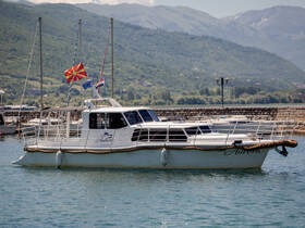 A beautiful view of the 'Aurora' boat docked in a serene harbor, surrounded by stunning mountainous scenery — perfect for exploring the waters.