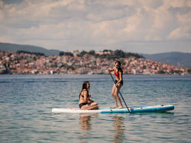 Two friends enjoy paddleboarding on a calm lake, showcasing a perfect day of water fun and adventure.
