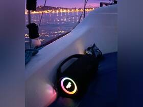 A colorful portable speaker sits on the deck of a boat, perfect for enhancing the onboard experience during evening cruises.