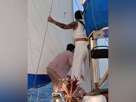 A couple actively sailing on a boat, adjusting the sails against a beautiful ocean backdrop — perfect for adventure seekers and sailing enthusiasts.