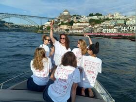 A lively group of friends celebrates on a boat, raising drinks against the stunning backdrop of a riverside cityscape — perfect for memorable outings and celebrations.