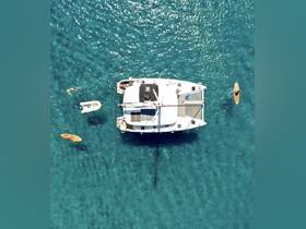Aerial view of a catamaran surrounded by clear turquoise waters, with guests paddleboarding and enjoying the vibrant marine environment — perfect for adventure seekers and water enthusiasts.