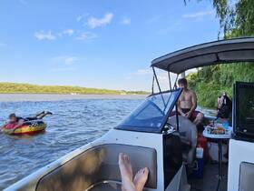 A child enjoys tubing while another person relaxes on the boat, capturing the essence of summer fun on the water.