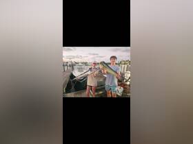 Two young anglers proudly display their impressive catch at the dock, celebrating a successful fishing trip — a perfect moment for fishing enthusiasts.
