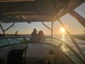 A couple enjoys a romantic sunset view from the deck of a boat, creating a perfect backdrop for memorable moments on the water.