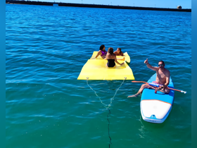 A fun day on the water with friends enjoying a floating mat and paddleboarding — perfect for summer adventures and relaxation.