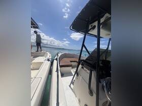 An interior view of a boat's helm and seating area, showcasing the console and a passenger enjoying the sunny day on the water.