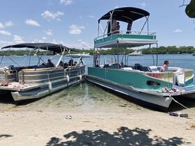 A lively scene featuring families enjoying a day on two pontoon boats at the beach, perfect for summer fun and water activities.