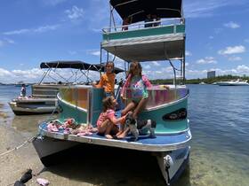 A group of children enjoys a sunny day on a pontoon boat, playing with a dog and soaking up the beach vibes — perfect for family outings and fun on the water.