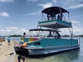 A lively group of children and adults enjoy a day at the beach aboard a pontoon boat, showcasing fun and relaxation in the sun.