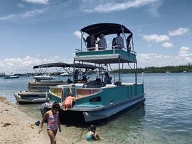 A lively scene at the beach with children playing in the water and adults enjoying a pontoon boat — perfect for family outings and summer fun.