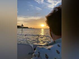 A serene sunset view from a boat, with a guest enjoying the tranquil waters — perfect for romantic evenings or peaceful getaways.