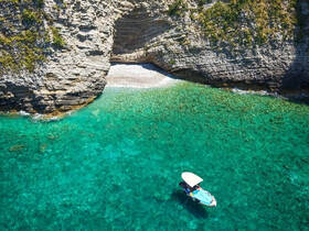 A scenic view of a small boat navigating through crystal-clear waters near a rocky coastline, showcasing the beauty of nature and perfect for exploring hidden coves.