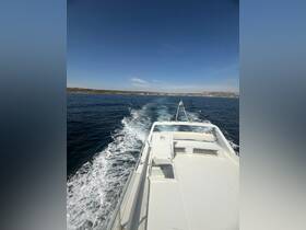 A view from the bow of a boat cruising through calm waters, showcasing the vessel's sleek design and the beautiful coastal scenery in the background.