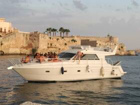 A lively group enjoys a fun day on a boat, celebrating with friends against a scenic backdrop of coastal architecture.