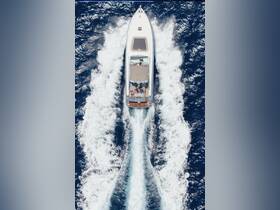An aerial view of a yacht cruising through deep blue waters, showcasing guests enjoying the ride — perfect for adventure seekers and luxury boat experiences.