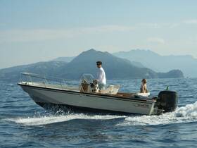 A couple enjoys a scenic boat ride on a sunny day, navigating through beautiful waters with mountains in the background — perfect for adventure seekers and romantic outings.