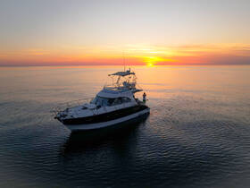A stunning aerial view of a yacht at sunset, showcasing the serene waters and vibrant sky, perfect for evening cruises.