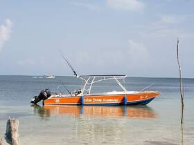 A vibrant speedboat is docked in calm waters, showcasing its sleek design and fishing gear, perfect for adventure seekers in Belize.