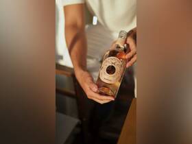 A close-up of a hand holding a bottle of wine, perfect for enhancing the onboard experience with refreshing beverages during a boat trip.