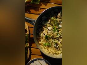 A delicious seafood pasta dish garnished with fresh herbs, perfect for enjoying on a boat trip or outdoor dining experience.