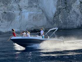 A lively group enjoys an exhilarating ride on a speedboat, capturing the thrill of adventure against a stunning coastal backdrop.