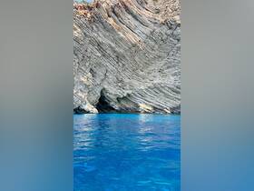 A stunning view of a rocky coastline reflected in crystal-clear blue waters, perfect for showcasing the natural beauty of coastal destinations.