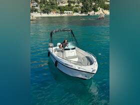 A woman navigates a sleek boat through crystal-clear waters, showcasing the perfect day for boating adventures along the stunning coastline.
