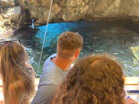 A group of friends enjoys a scenic view while exploring a cave, observing fish in the clear waters — a perfect adventure for nature lovers.