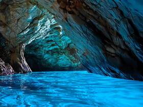 A stunning view of a cave with vibrant blue waters reflecting the intricate rock formations — a breathtaking destination for eco tours and exploration.
