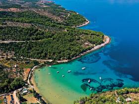 A stunning aerial view of a serene beach surrounded by lush greenery and crystal-clear waters, showcasing a perfect destination for relaxation and water activities.