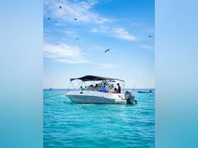 A lively group enjoys a day on the water aboard a motorboat, surrounded by stunning turquoise waters and a clear blue sky — perfect for summer adventures.