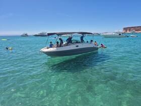 A lively scene featuring a group enjoying a day on the water, with a boat anchored nearby and swimmers having fun in the clear turquoise sea.