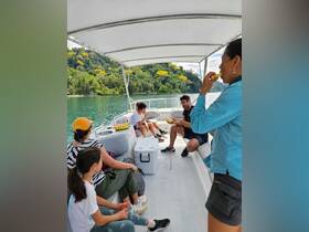 A lively group enjoys snacks aboard a boat, surrounded by lush greenery — perfect for family outings and fun adventures on the water.