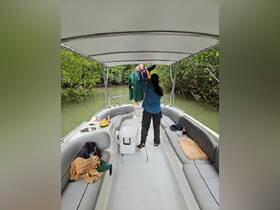 A joyful group poses for a photo on a boat in a mangrove setting, capturing a memorable moment during their adventure.