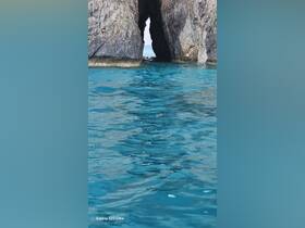 A stunning view of a rock formation creating a natural archway over crystal-clear turquoise waters, perfect for showcasing the beauty of coastal destinations.