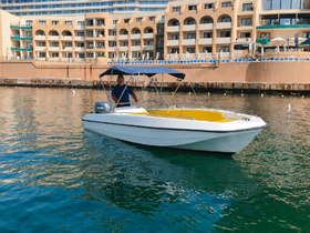 A person navigates a small boat in calm waters near a marina, showcasing a perfect day for boating adventures.
