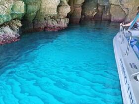 A stunning view of turquoise waters inside a cave, with a boat partially visible — a perfect spot for exploring and enjoying the natural beauty of the surroundings.