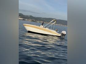 A sleek speedboat anchored in calm waters, showcasing its elegant design against a scenic backdrop of hills and coastline.