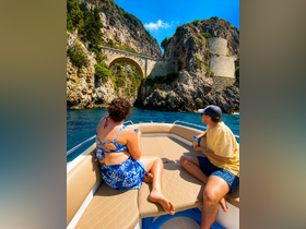 A couple enjoys a scenic boat ride, taking in the stunning coastal views while relaxing on the deck with snacks. Perfect for exploring beautiful destinations.