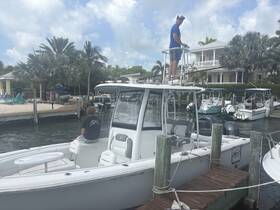 A young person relaxes on the deck of a boat while another prepares for fishing, set against a scenic dockside backdrop — perfect for a day of fun on the water.