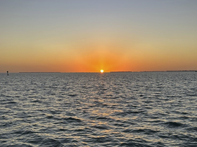 A stunning sunset over calm waters, creating a picturesque scene perfect for evening boat cruises or romantic getaways.