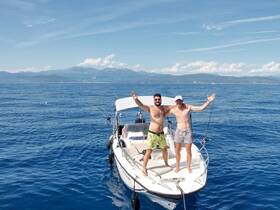 Two friends celebrate on a boat in the open ocean, showcasing a fun fishing adventure with stunning views of the coastline.
