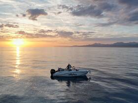 A serene sunset view featuring a boat on calm waters, with individuals enjoying the tranquil atmosphere — perfect for romantic evenings or peaceful getaways.
