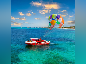 A thrilling parasailing adventure unfolds as a colorful parachute soars above a vibrant blue sea, showcasing the excitement of water sports.