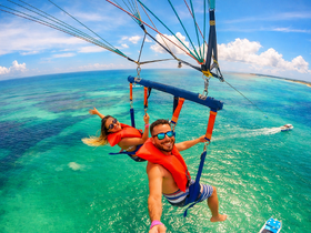 A couple enjoys an exhilarating parasailing adventure over the stunning turquoise waters, capturing the thrill of ocean activities and breathtaking views.