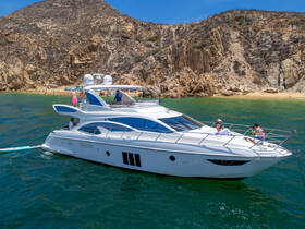 A lively group enjoys a sunny day aboard a luxurious yacht, with a beautiful beach backdrop — perfect for summer celebrations and relaxation on the water.