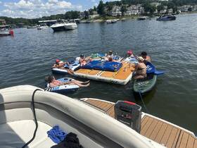 A lively group enjoys a fun day on the water, relaxing on floating mats and soaking up the sun — the perfect summer getaway.